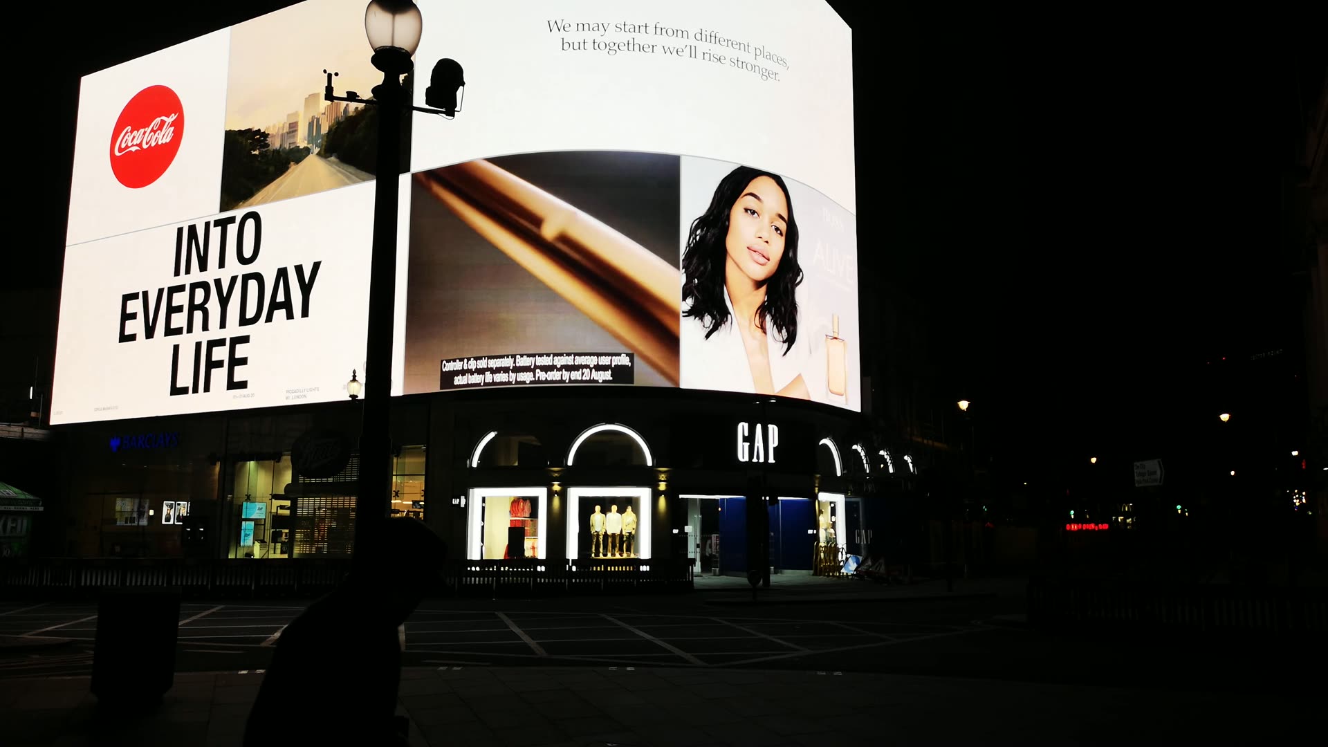 Illuminated advertising screens above a city street at night